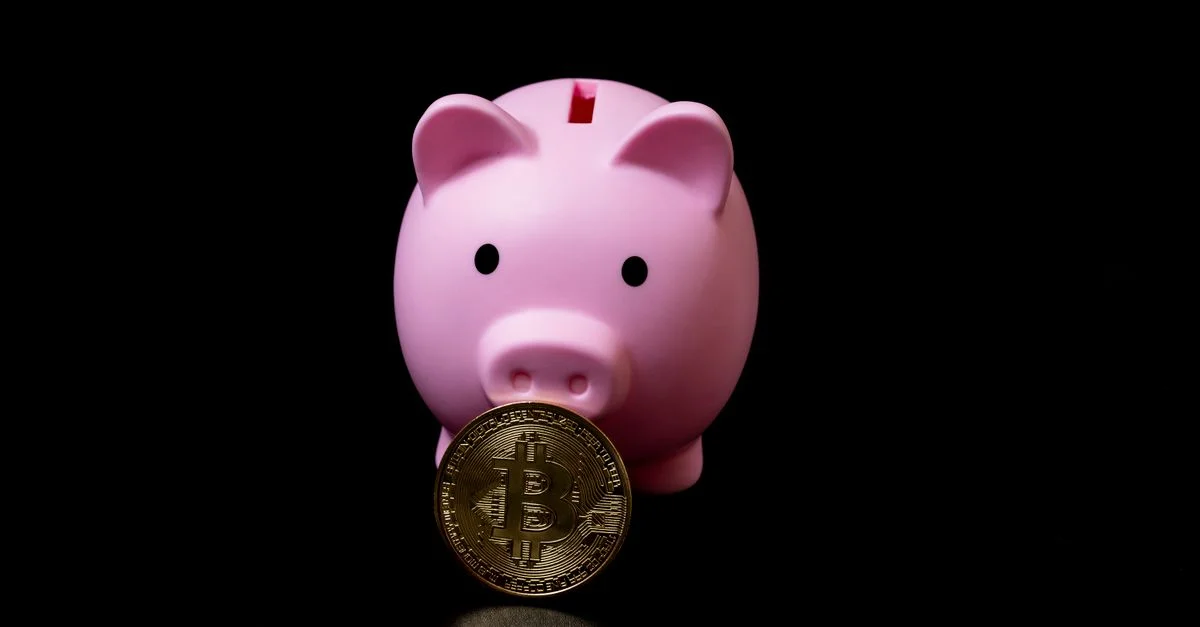 Tirelire rose tenant une pièce de bitcoin symbolisant les investissements numériques modernes.