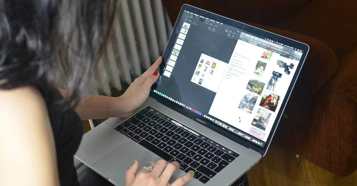Une femme se concentre sur son ordinateur portable, travaillant sur un projet dans un environnement intérieur confortable.